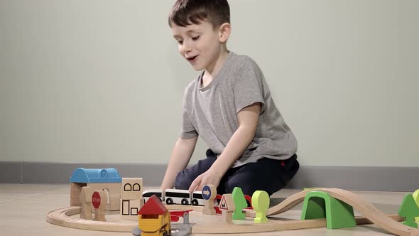 Cute boy plays with a wooden train, takes him across the bridge on flights.