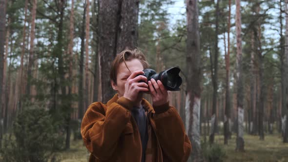 A Young Blond Photographer Takes Pictures in the Woods