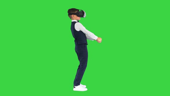 Boy in Formal Wear Playing the Sword Game in Virtual Reality Goggles on a Green Screen Chroma Key