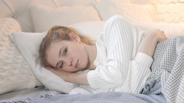 Pensive Thinking Young Woman lying in Bed