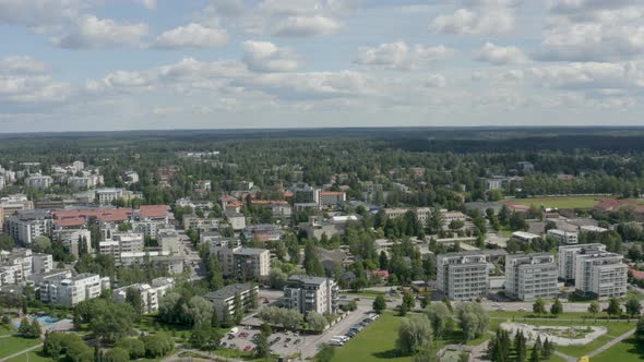 Slow aerial view above a city near Helsinki, Finland with cars passing quickly on the road.