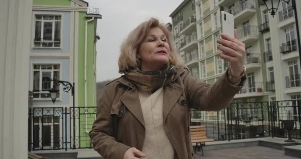 Close-up Portrait of Happy Caucasian Retiree Talking at Selfie Camera and Showing Surroundings