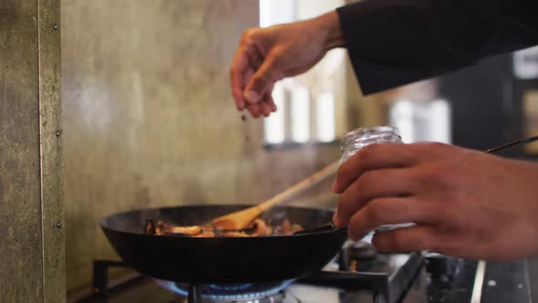 Mixed race male chef preparing a dish and smiling in a kitchen