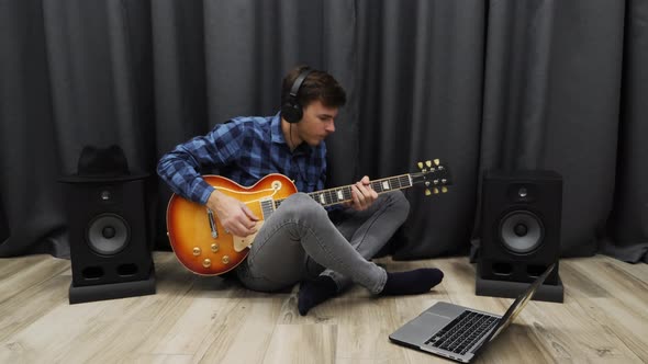 Young Man gets angry while practicing a song on electric guitar at home recording studio throws pick