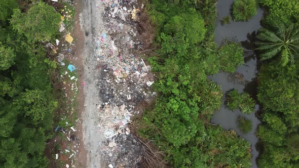 Aerial view rubbish beside green lush bush.