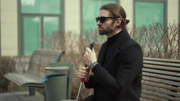 Blind Man with a Cane Sitting on a Bench