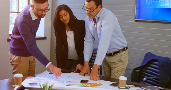 Executives discussing over blueprint in conference room