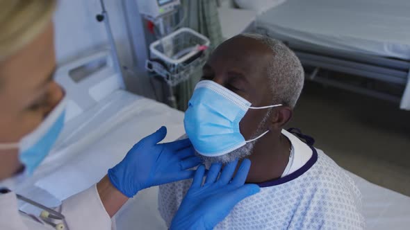 Caucasian female doctor examining throat of african american senior male patient wearing face mask