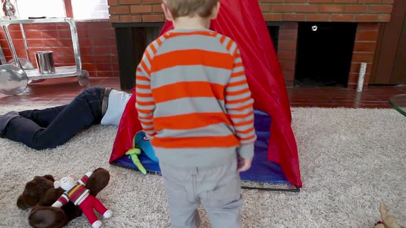 Father and son playing in teepee in living room