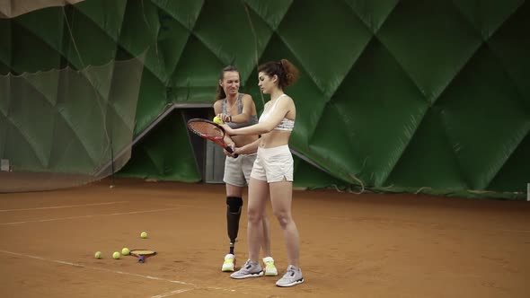 A Beautiful Female Coach with a Prosthesis on Her Leg Shows Her Ward the Nuances of the Ball Hitting