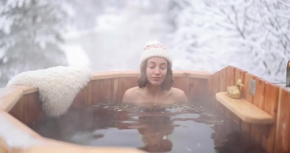 Woman Relaxing in Hot Bath at Snowy Mountains