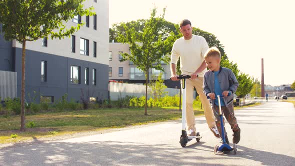 Happy Father and Son Riding Scooters in City