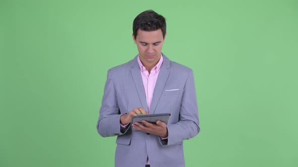 Happy Young Handsome Businessman Thinking While Using Digital Tablet