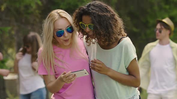 Young Beautiful Women Viewing Photos on Smartphone in Park, Party, Relax