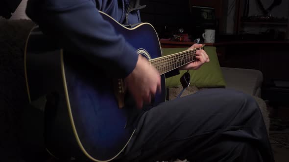 Man Plays a Pick on a Modern Guitar in the Dark