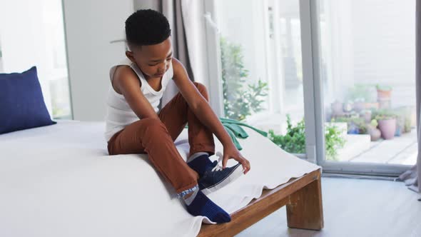 African american boy standing in bedroom getting dressed