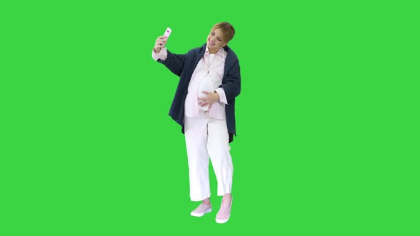 Happy Young Pregnant Woman Taking Selfie on a Green Screen, Chroma Key.