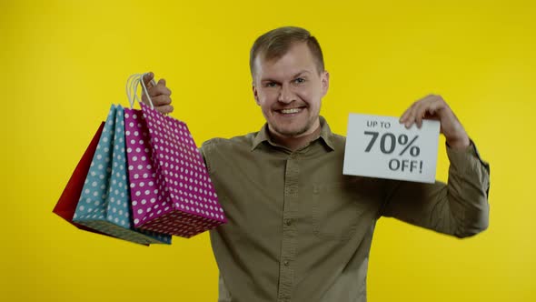 Man Showing Up To 70 Percent Off Inscription and Shopping Bags, Looking Satisfied with Low Prices