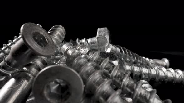 Pile of Steel Chrome Screws Rotating on Isolated Black Background