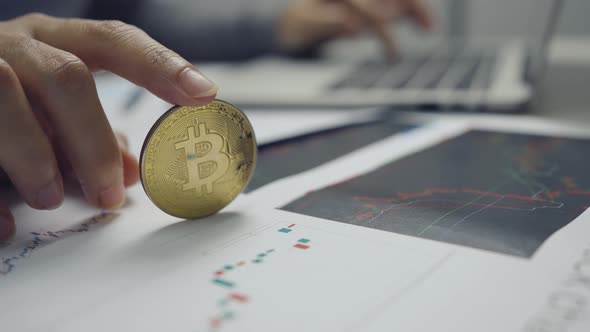 Woman working with a hand holding a gold bitcoin coin.