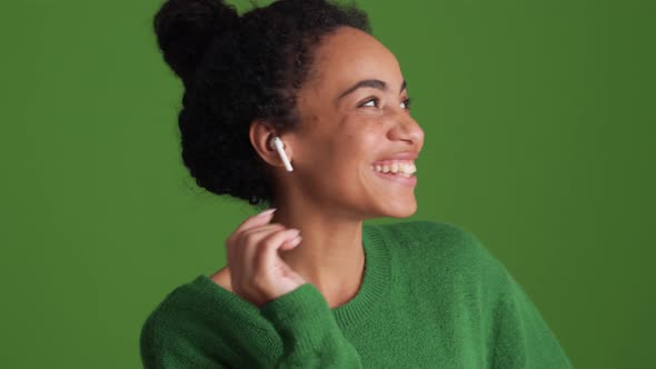 Laughing African woman in green shirt talking in headphones