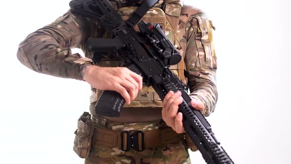 Man in combat camouflage and body armor attaches an ammunition magazine