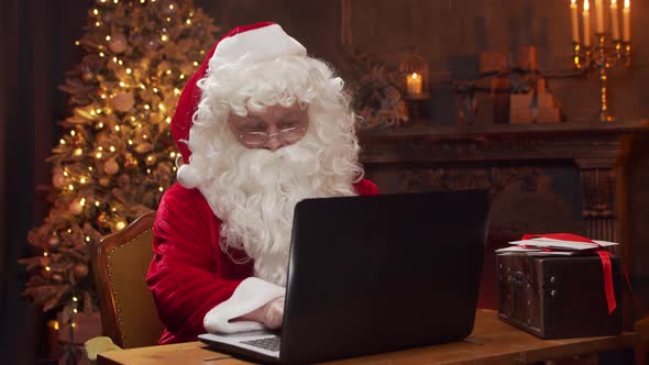 Workplace of Santa Claus. Cheerful Santa is working while sitting at the table.