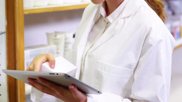 Pharmacist using digital tablet while checking medicine