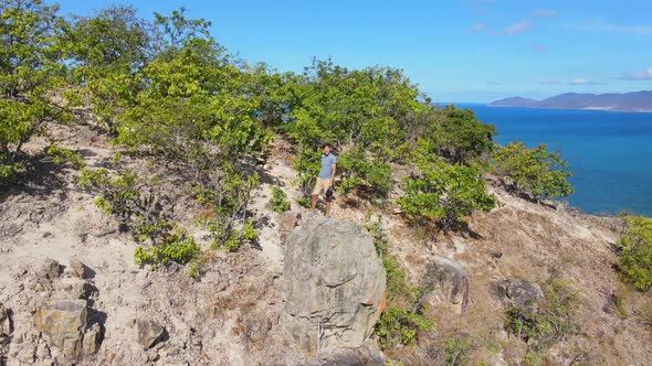 Aerial Shot of a Young Man Sitting on a Rock in Mountains. Hiking Concept