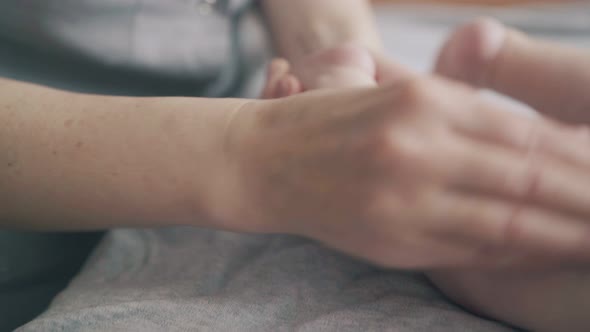 Professional Pediatrician Massages Newborn Boy on Table