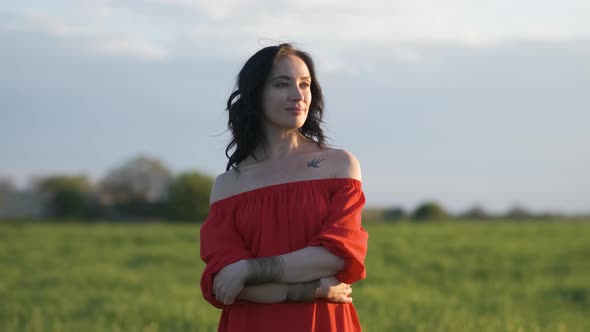 Portrait of a Beautiful Spanish Brunette Woman in a Red Dress at Sunset in a Wheat Field at Day