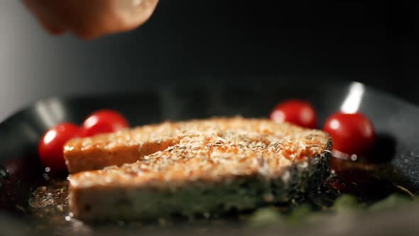 A Salmon Fillets on a Grill Plate is Sprinkling Spices