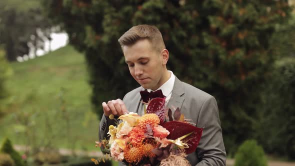 Groom Goes Down the Alley Between Bushes with a Wedding Bouquet to His Beloved Bride First Meeting