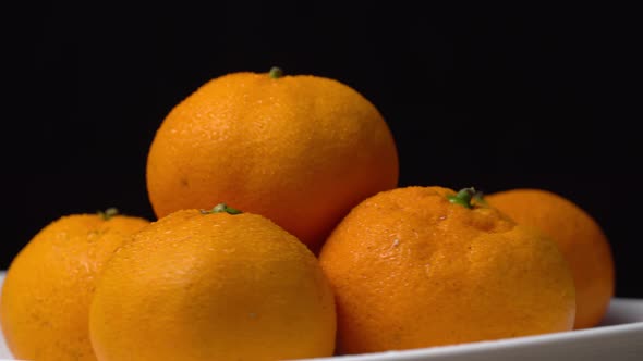 close-up of tangerines spinning on a turntable on a plate on a black background