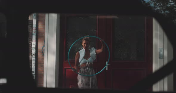 Woman Spins Hula Hoop infront of Red door