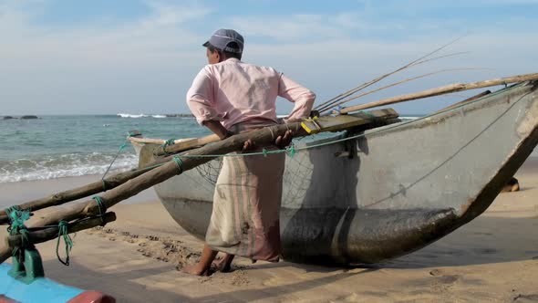 Man Pulls Traditional Hand Made Fishing Boat Against Sea