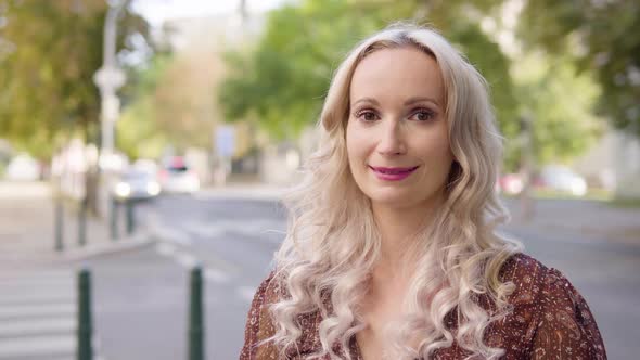 A Middleaged Caucasian Woman Smiles at the Camera and Poses in an Urban Area  Closeup