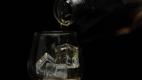 Pouring Alcohol Drink Whiskey, Cognac Into Glass. Black Background. Slow Motion