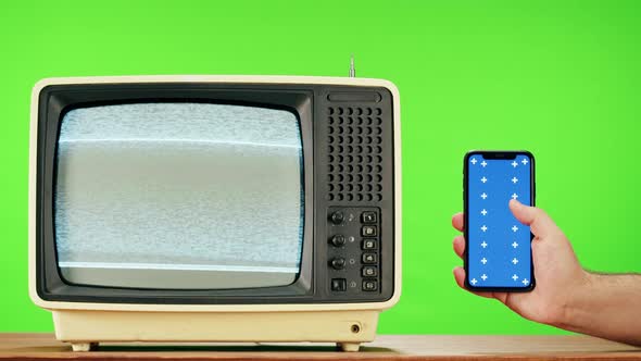 Old Television with Grey Interference Screen on Green Background and Smartphone with Blue Chroma Key