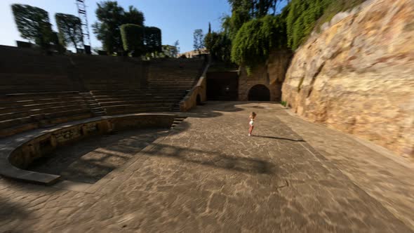 Drone Shot of a Girl in a White Tight Suit Staying in the Ancient Amphitheater