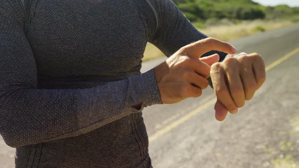 Triathlete man using smartwatch on a sunny day