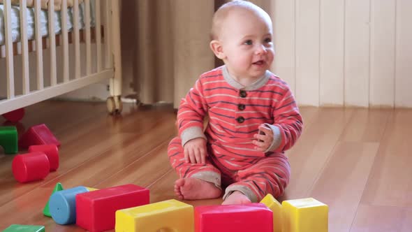 Little Baby Clapping His Hands Playing with Educational Colorful Toys at Home Sitting on Floor