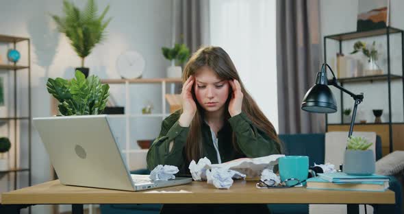 Female Person Feeling Headache and Massaging Her Temples During working