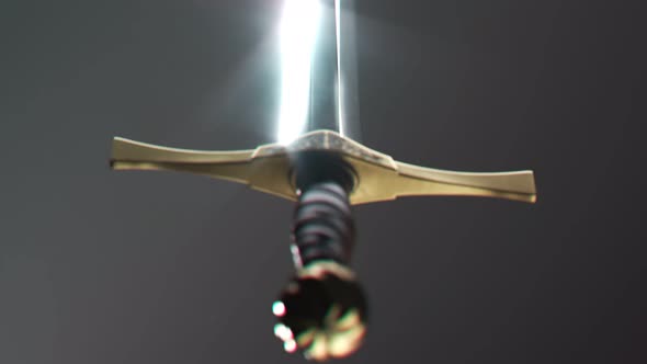 Old medieval sword shining in a spotlight. Light reflects in a sharp blade. 4KHD