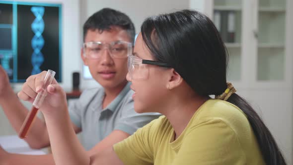 Young Asian Boy And Girl Learning Science Experiment. They Are Holding Test Tubes And Talking