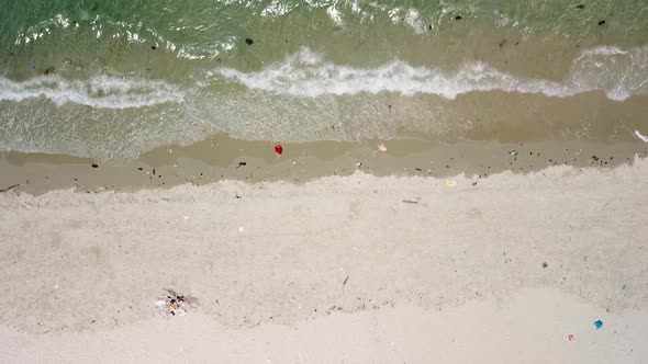 Aerial Top Down of Water Edge in the Beach with Plastics and Waste on the Sand.