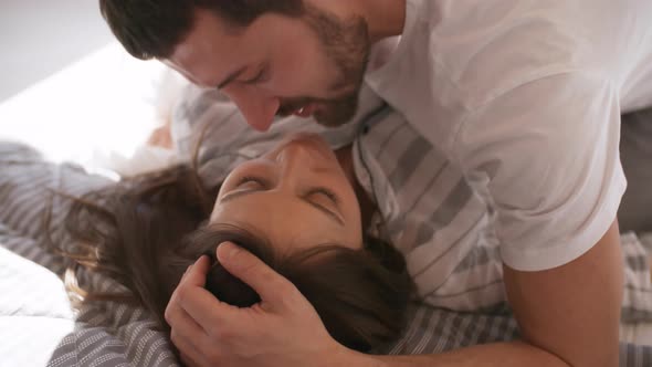 Affectionate Couple Kissing in Bed in Morning