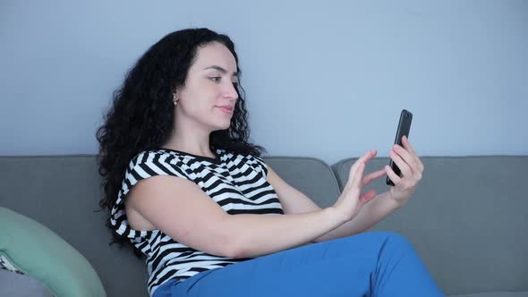 Woman Typing on Phone Sitting on Sofa at Home, Businesswoman Sits at Home Types on Smartphone Checks