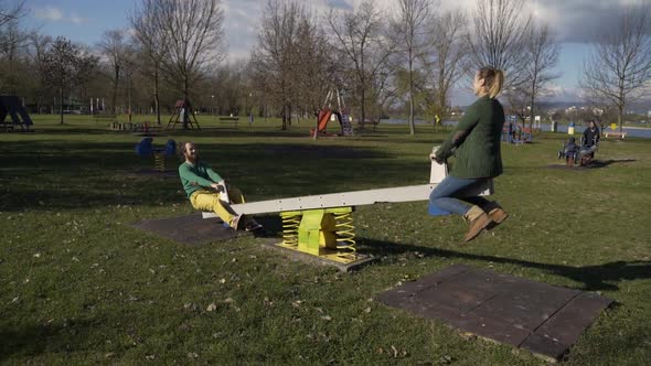 Couple playing together at seesaw in public playground, Zagreb, Croatia.