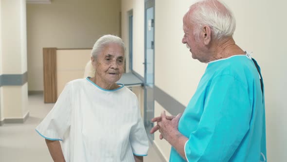 Pair of old people standing in hospital and talking